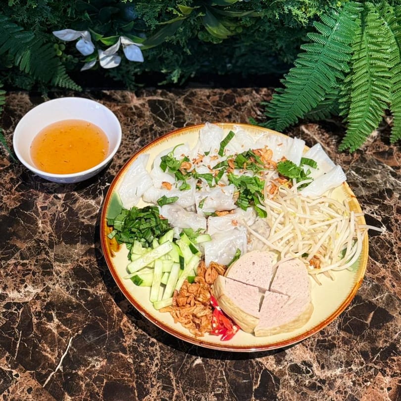 Vietnamese Banh Cuon with sliced pork, bean sprouts, cucumbers, and a side of dipping sauce.